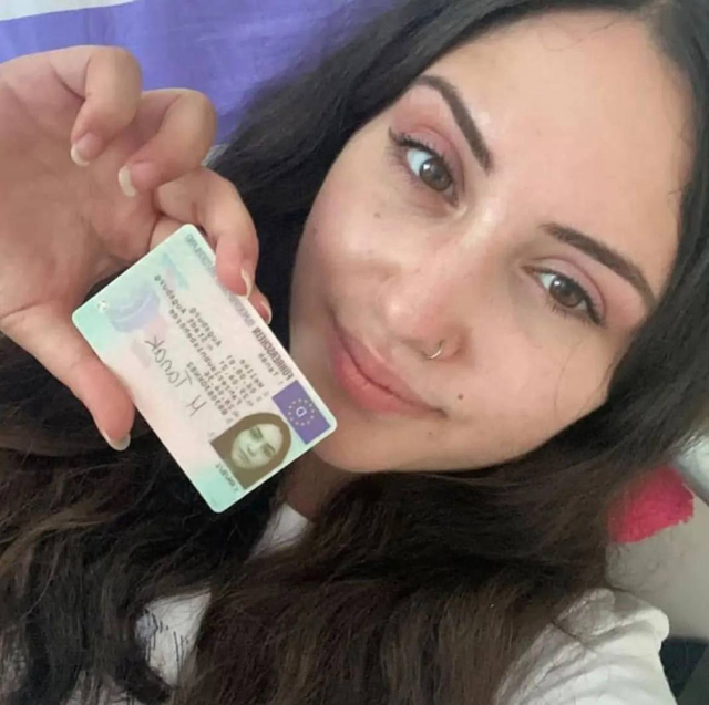 Frau hält eine Führerscheinkarte neben ihr Gesicht